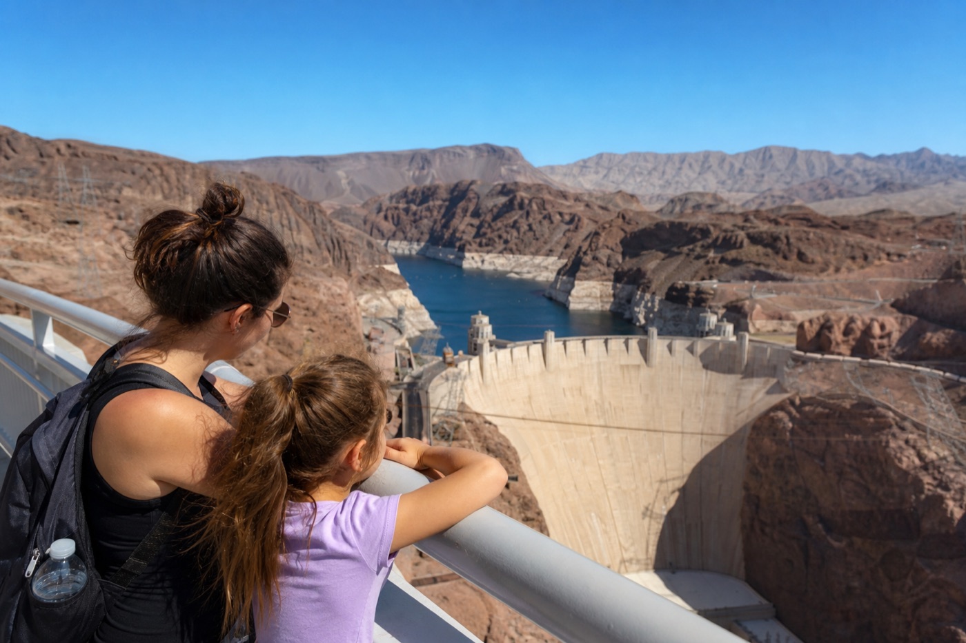 Parent and child looking across Hoover Dam from a safe overlook railing
